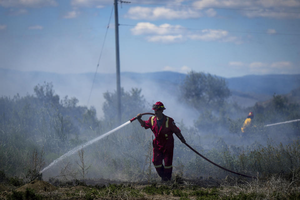 A firefighter directs water on a grass fire burning on an acreage behind a residential property in Kamloops, British Columbia, Canada, on Monday, June 5, 2023. (Darryl Dyck/The Canadian Press via AP)