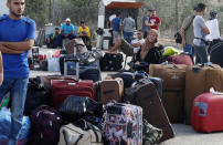 Passengers sit next to their luggage as they wait to cross the border to the Egyptian side of Rafah crossing, in Rafah, Gaza Strip, Tuesday, Aug. 11, 2020. Egypt reopened Rafah Crossing for three days starting Tuesday for humanitarian cases in and out of the Gaza Strip, including medical patients and people who had Egyptian and international citizenship. The border was closed since March. (AP Photo/Adel Hana)