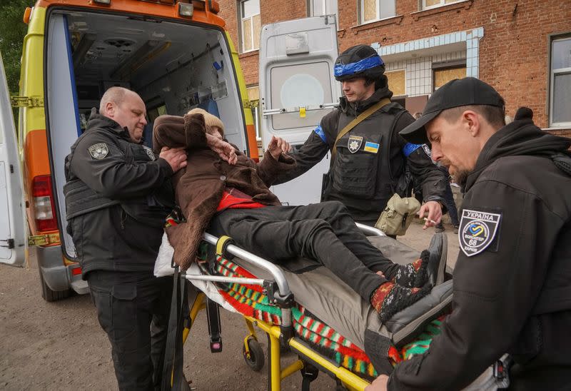 Police officers help a local resident during an evacuation to Kharkiv due to Russian shelling near the town of Vovchansk