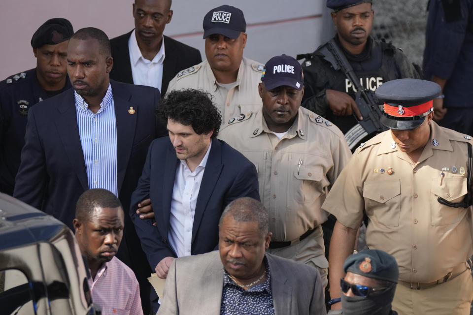 FILE - Sam Bankman-Fried, center left, founder of the failed cryptocurrency exchange FTX, is escorted out of Magistrate Court after a hearing in Nassau, Bahamas, Monday, Dec. 19, 2022. FTX was supposed to be the crown jewel of the Bahamian government's push to be the global destination for all things crypto, after years of having an economy overly reliant on tourism and banking. (AP Photo/Rebecca Blackwell, File)