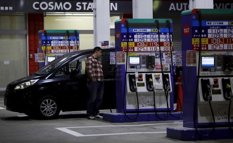 A man stands to wait for refueling for his car at Cosmo Energy Holdings' Cosmo Oil service station in Tokyo, Japan, December 16, 2015. REUTERS/Yuya Shino