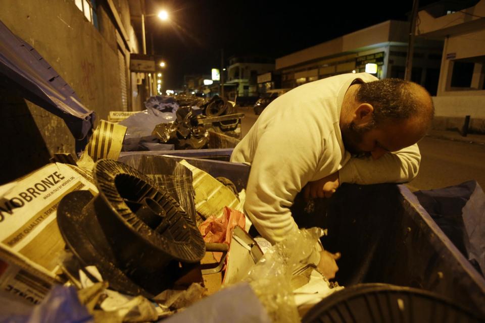 In this Monday, Feb. 10, 2014 photo Constantinos Sapkas, 39, searches a recycle bin for metal in the depressed Perama area, on the fringes of Athens' port of Piraeus. Sapkas lost his last job in March 2010, and now spends his nights rummaging through Perama’s rubbish bins for metal to sell for scrap. That earns him up to two euros a day. Perama’s unemployment is among the worst in Greece, where the nationwide figure for November was 28 percent, according to the statistical authority on Thursday, Feb. 13, 2014. (AP Photo/Thanassis Stavrakis)