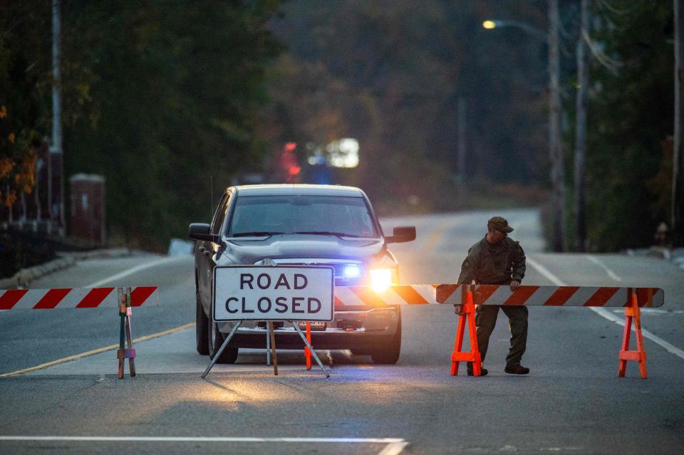 A law enforcement official moves a roadblock into place near Schemengees Bar where a shooting took place in Lewiston, Maine, on Oct. 26, 2023.