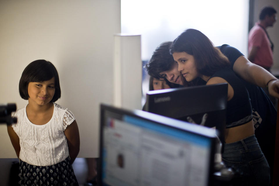 In this Dec.15, 2018 photo, accompanied by her sisters, at right, Emma a transgender girl, left, a student of the Amaranta Gomez school, updates her identity card information in the national registry of persons, in Santiago, Chile. In recent years, the families of trans children have demanded greater acceptance, a call that recently led to the approval of a law that allows people over the age of 14 to change their name and gender in official records with the consent of their parents or legal guardians. (AP Photo/Esteban Felix)