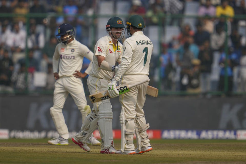 Australia's Travis Head, center, greets Usman Khawaja after he scored half century during the first day of the second cricket test match between India and Australia in New Delhi, India, Friday, Feb. 17, 2023. (AP Photo/Altaf Qadri)