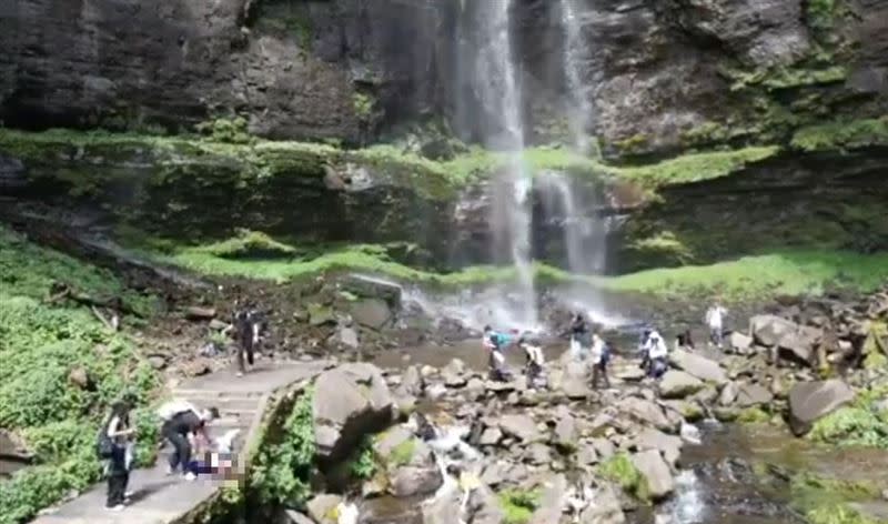 一群遊客在屋瓦山風景區的瀑布下欣賞風景，一個飛落的石塊正巧砸中女遊客頭部，當場血流如注。(圖／翻攝自Ｘ)