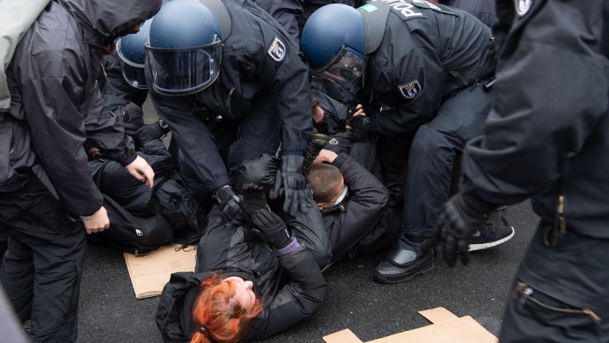 Polizisten lösen eine Sitzblockade von Gegen-Demonstranten auf.