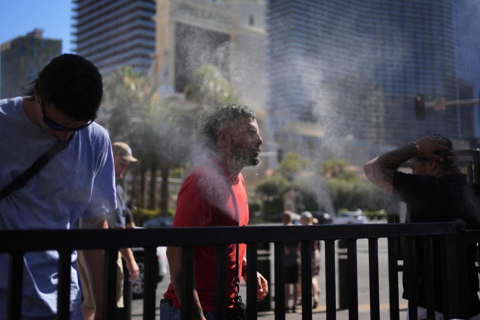 FILE - People cool off in misters along the Las Vegas Strip, Sunday, July 7, 2024, in Las Vegas. Used to shrugging off the heat, Las Vegas residents are now eyeing the thermometer as the desert city is on track Wednesday to set a record for the most consecutive days over 115 degrees (46.1 C) amid a lingering hot spell that's expected to continue scorching much of the U.S. into the weekend. (AP Photo/John Locher, File)