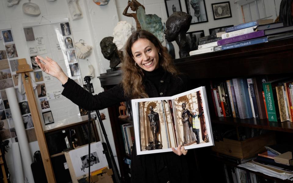 Poppy Field with her project book featuring a picture of the sculptures at the Royal Albert Hall