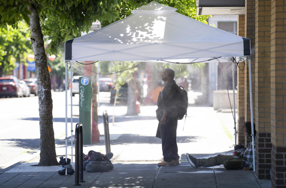 People use a misting tent outside of Blanchet House in downtown Portland, Ore., as a heat wave continues Monday, July 8, 2024. (Dave Killen/The Oregonian via AP)