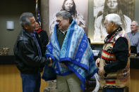 Attorney General William Barr, center, shakes hands with Vernon Finley, left, and Tony Incashola, right, after they presented him with a blanket during a Confederated Salish and Kootenai Tribes council meeting, Friday, Nov. 22, 2019, on the Flathead Reservation in Pablo, Mont. (AP Photo/Patrick Semansky)