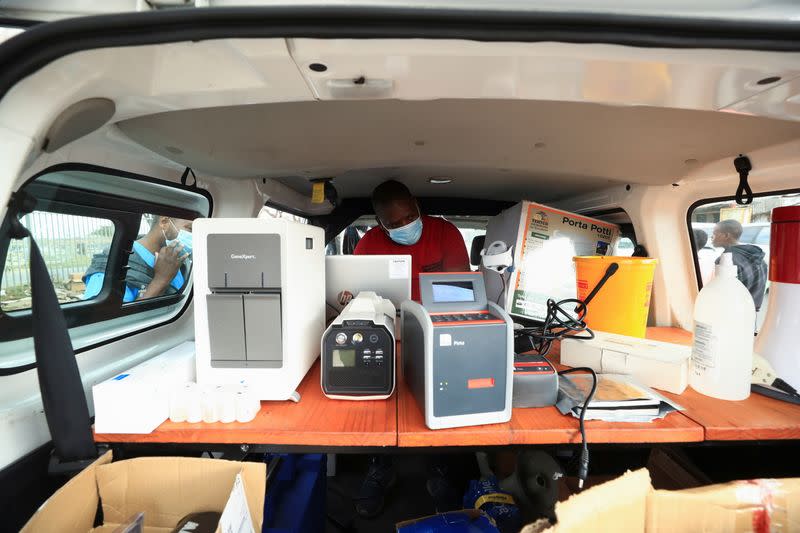 Healthcare workers monitor machines analysing tuberculosis samples at a mobile clinic in Gugulethu township near Cape Town