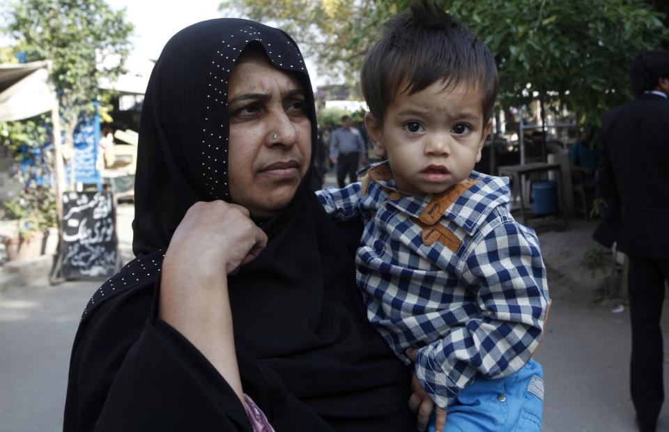 Saeeda Bibi carries her nine-month-old grandson Musa Khan as he arrives to appear in a court in Lahore