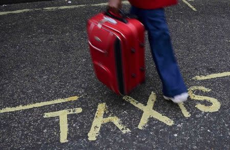 A traveller walks over a "Taxi" sign on the road outside Victoria Coach Station in central London, Britain October 28, 2016. REUTERS/Toby Melville