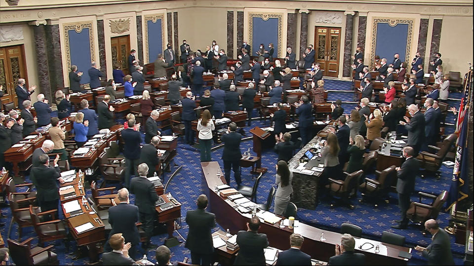 In this image from video, senators and staff give a standing ovation to U.S. Capitol Police offer Eugene Goodman, standing in the far back row, shortly before voting to award him the Congressional Gold Medal for his actions during the Jan. 6 riot, as the Senate took a break from the second impeachment trial of former President Donald Trump in the Senate at the U.S. Capitol in Washington, Friday, Feb. 12, 2021. (Senate Television via AP)