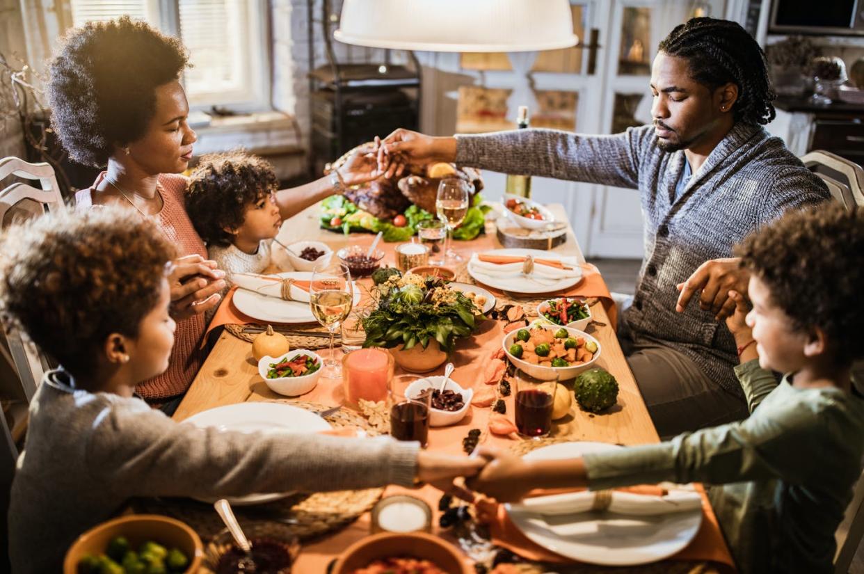 <span class="caption">A family holds hands and prays before a Thanksgiving meal.</span> <span class="attribution"><a class="link " href="https://www.gettyimages.com/detail/photo/religious-black-family-saying-grace-before-royalty-free-image/1176300326?adppopup=true" rel="nofollow noopener" target="_blank" data-ylk="slk:skynesher/E+ via Getty Images;elm:context_link;itc:0;sec:content-canvas"> skynesher/E+ via Getty Images</a></span>