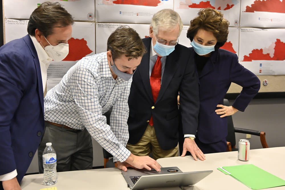 Republican Senate candidate Sen. Mitch McConnell, second from right, and his wife, Elaine Chao, right, look on as aides show him the election results in Louisville, Ky., Tuesday, Nov. 3, 2020. (AP Photo/Timothy D. Easley)
