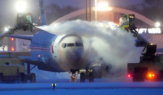 Workers de-ice an American Airlines plane Thursday as high winds whip around 7.5 inches of new snow at Minneapolis-St. Paul International Airport.