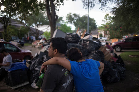 Luis Sanchez and Elizabeth Gallegos embrace after clearing furniture from the house of a family member left flooded by Tropical Storm Harvey in Houston, Texas, U.S. September 4, 2017. REUTERS/Adrees Latif