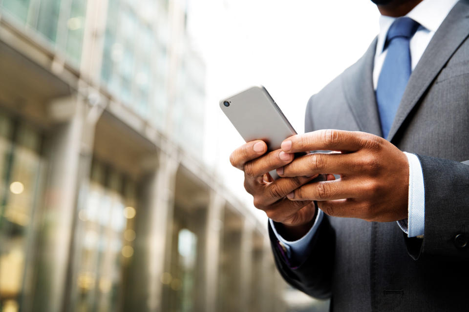 Man in a suit and tie looking at his cellphone in front of a building