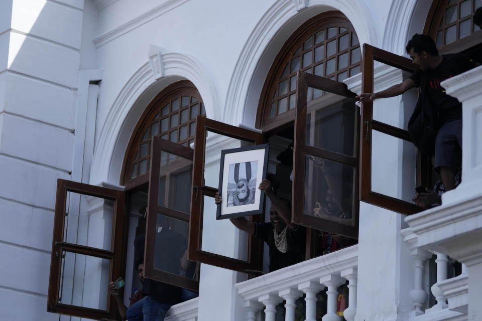 A protester holds a portrait of former Sri Lankan prime minister Mahinda Rajapaksa upside down after storming the Prime Minister Ranil Wickremesinghe's office, demanding he resign after president Gotabaya Rajapaksa fled the country amid economic crisis in Colombo, Sri Lanka, Wednesday, July 13, 2022. Rajapaksa fled on a military jet on Wednesday after angry protesters seized his home and office, and appointed Prime Minister Ranil Wickremesinghe as acting president while he is overseas. Wickremesinghe quickly declared a nationwide state of emergency to counter swelling protests over the country's economic and political collapse. (AP Photo/Eranga Jayawardena)