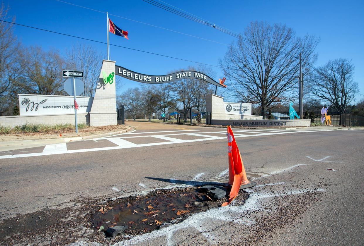 A pothole sits on Museum Boulevard in front of the entrance to LeFleur’s Bluff State Park and LeFleur Museum District in Jackson, Miss., Friday, Jan. 19, 2023. Just north is a second pothole with a traffic barrel sitting in it.