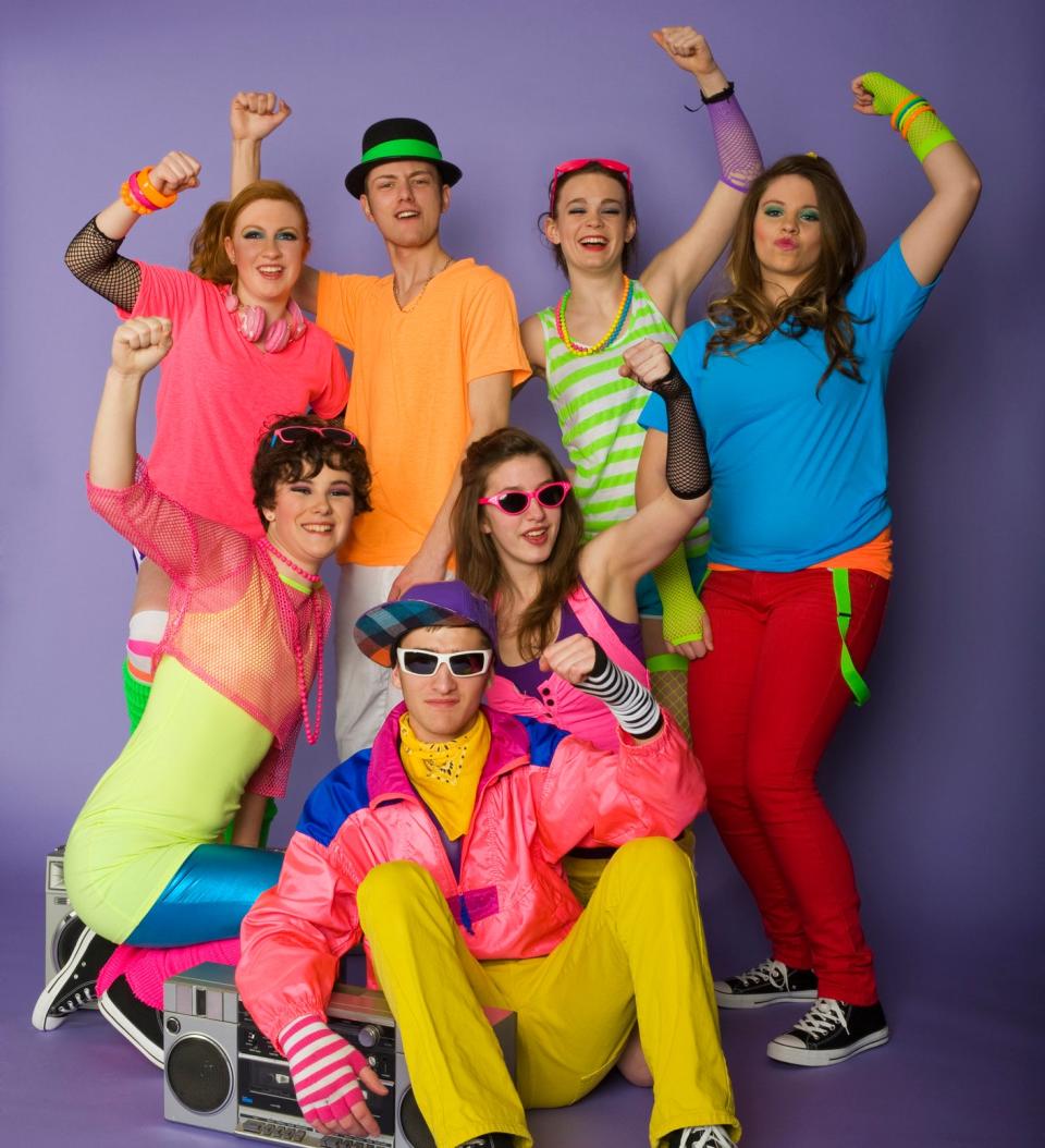 Group in vibrant 80s attire with neon accessories, boombox, gestures energetically