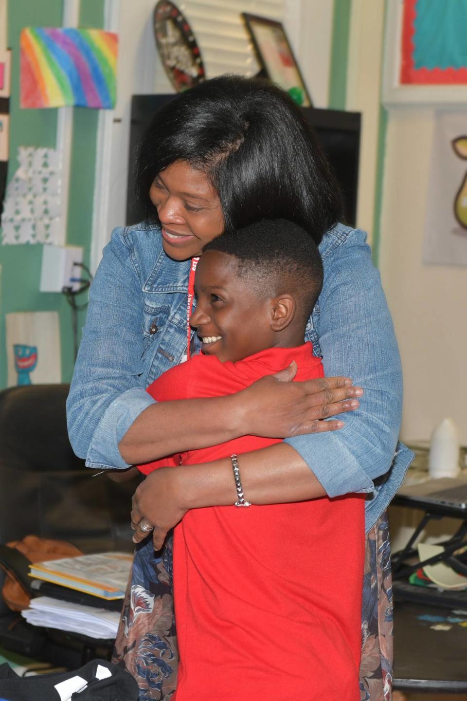 Stacey McClary of the Wynnton Arts Academy hugs one of her students after she was surprised in her classroom March 14, 2024, with the announcement that she is among the three finalists for Muscogee County School District’s Teacher of the Year award.