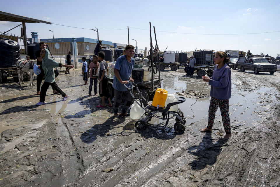 Palestinians gather to fill water jugs at a makeshift tent camp in Deir al-Balah, central Gaza Strip, Thursday, Aug. 29, 2024. (AP Photo/Abdel Kareem Hana)