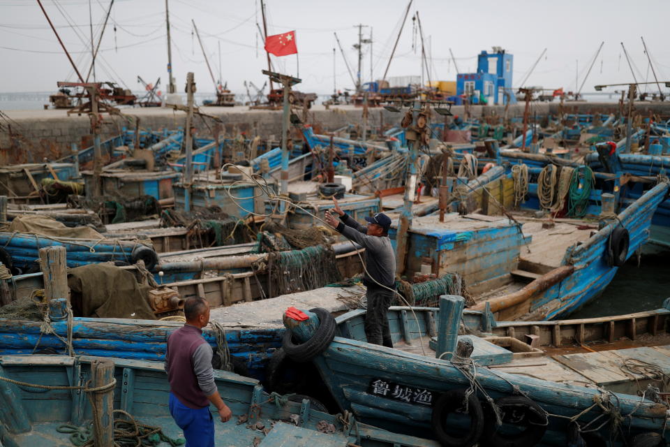 在中國大陸山東省青島市外的黃海海域，油輪A Symphony與散貨船Sea Justice發生相撞溢油事故後，漁民站在沿岸碼頭的船上整頓。圖片來源：Reuters。