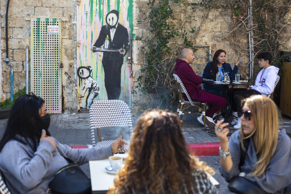 People eat in a restaurant as restrictions are eased following months of government-imposed shutdowns, in Tel Aviv, Israel, Sunday, March 7, 2021. Israel reopened most of its economy Sunday as part of its final phase of lifting coronavirus lockdown restrictions, some of them in place since September. (AP Photo/Ariel Schalit)