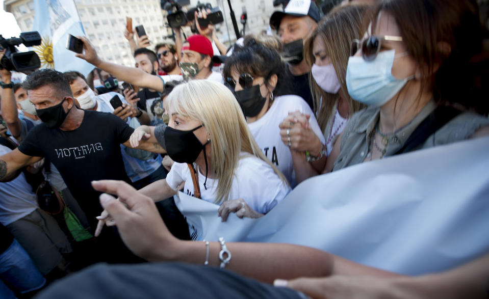 Claudia Villafañe (centro), la exesposa del extinto astro del fútbol Diego Maradona, es rodeada por hinchas durante una manifestación para reclamar respuestas en la investigación por la muerte de Maradona en Buenos Aires, el miércoles 10 de marzo de 2021. (AP Foto/Natacha Pisarenko)