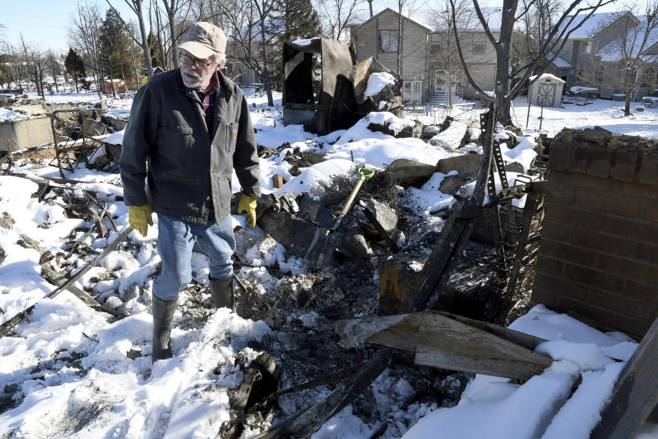 FILE - Rex Hickman sifts through the rubble of his burned home in Louisville, Colo., Sunday, Jan. 2, 2022. Some homeowners recovering from Colorado's most destructive wildfire in history, which decimated entire neighborhoods near Denver late last year, say they could end up paying tens of thousands of dollars more to rebuild because of environmentally sustainable construction standards passed shortly before the blaze. (AP Photo/Thomas Peipert, File)