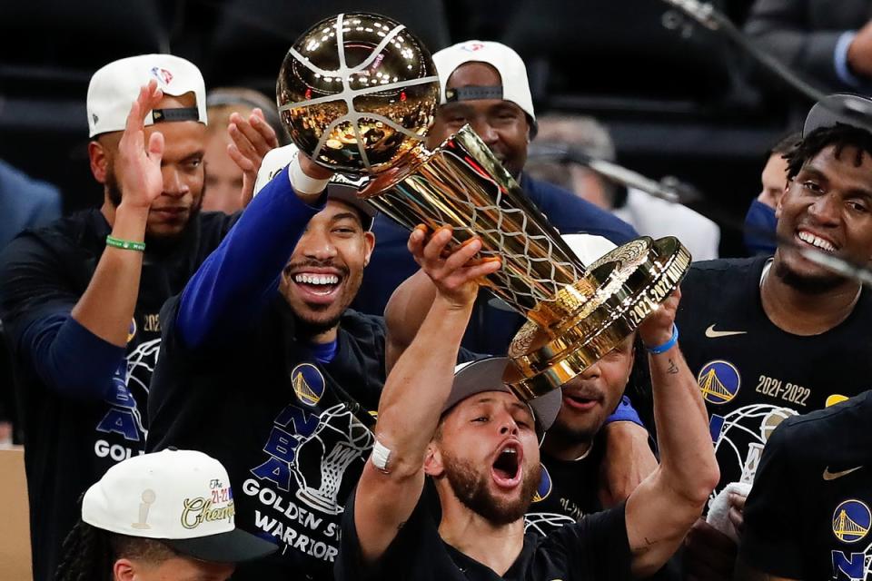 Steph Curry hoists the NBA trophy aloft  (AP)