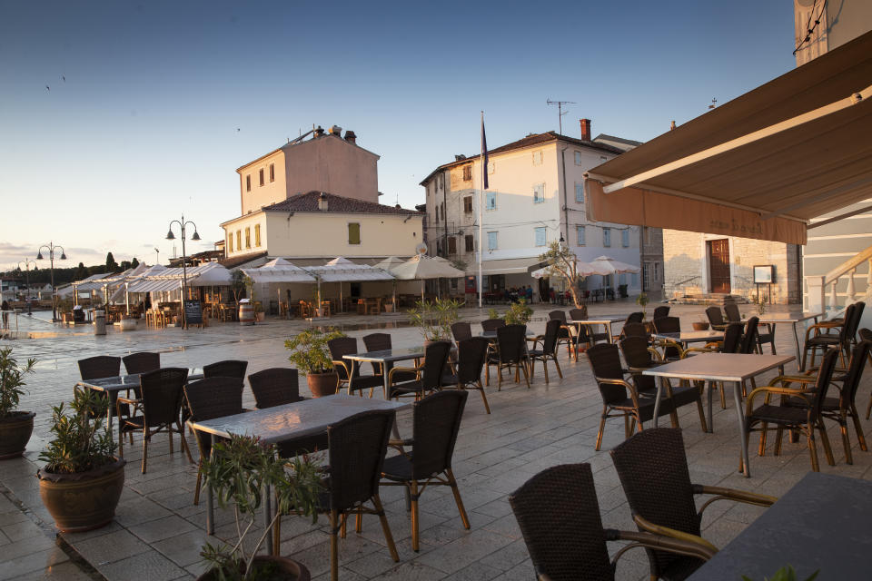 Cafes and restaurants are empty in the harbor in Fazana, Croatia, Tuesday, May 26, 2020. The "Our Dream Their Smile" group has helped people in the tourism-dependent area in the Adriatic survive as the outbreak closed down borders, shutting down hotels, restaurants and other businesses that normally thrive in virus-free times. (AP Photo/Darko Bandic)