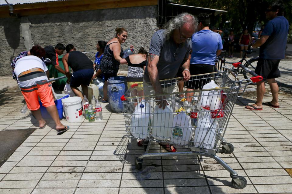 Residentes reúnen agua de una boca de incendio en una comuna de Santiago, Chile, el lunes 27 de febrero de 2017. Millones de personas se quedaron sin agua potable en la zona metropolitana de la capital chilena tras inundaciones y deslaves, que provocaron escasez. (AP Foto/Esteban Félix)