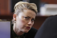 Actor Amber Heard speaks with a legal team member at the Fairfax County Circuit Courthouse in Fairfax, Va., Wednesday, May 25, 2022. Actor Johnny Depp sued his ex-wife Amber Heard for libel in Fairfax County Circuit Court after she wrote an op-ed piece in The Washington Post in 2018 referring to herself as a "public figure representing domestic abuse." (Evelyn Hockstein/Pool photo via AP)