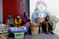 In this April 17, 2020, photo, street vendors wear face masks amid fears of the new coronavirus outbreak, at a market in Bali, Indonesia. The world's fourth most populous nation now has the highest number of recorded fatalities from the COVID-19 disease in Asia after China, and testing for the viral infection remains among the lowest in the region. (AP Photo/Firdia Lisnawati)