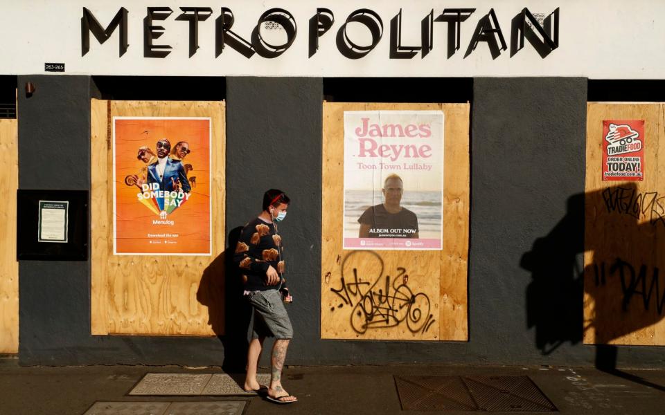 A man walks past a boarded up hotel in Melbourne