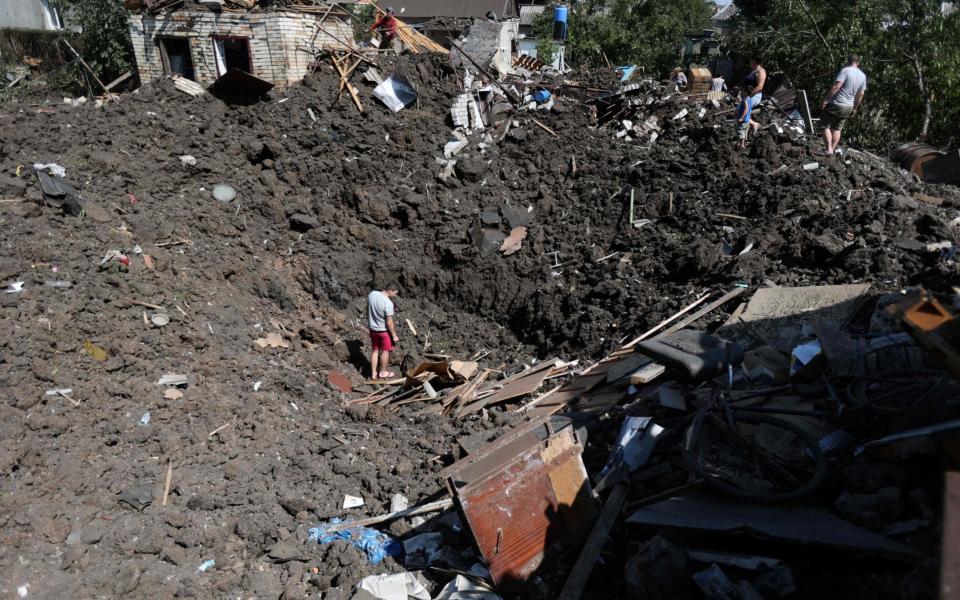 Residents inspect a crater following a strike in Druzhkivka village, Donetsk region - ANATOLII STEPANOV/AFP