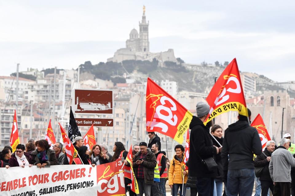 People wave the flags of French trade union General Confederation of Labour (CGT), with the Notre-Dame de la Garde in the background, during a demonstration to protest against the pension overhauls, in Marseille.