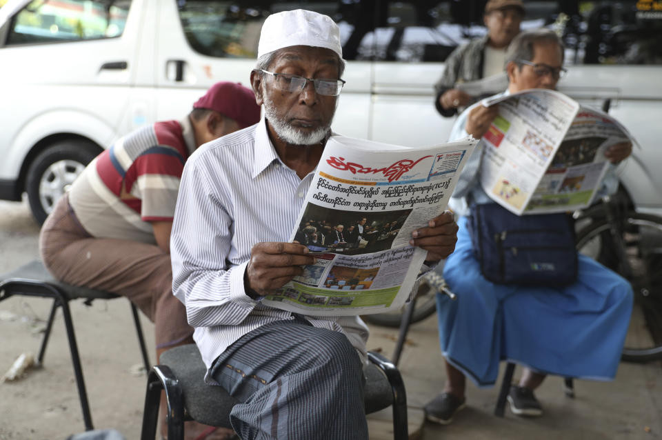 People read newspapers with front pages leading with Myanmar leader Aung San Suu Kyi at the International Court of Justice hearing near a roadside journal shop Thursday, Dec. 12, 2019, in Yangon, Myanmar. Suu Kyi testified to the court that the exodus of hundreds of thousands of Rohingya Muslims to neighboring Bangladesh was the unfortunate result of a battle with insurgents. She denied that the army had killed civilians, raped women and torched houses. (AP Photo/Thein Zaw)