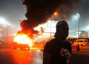 A soccer fan is seen near a police car, which was set on fire by fireworks, during clashes between soccer fans and security forces in front of a stadium on the outskirts of Cairo February 8, 2015. REUTERS/Al Youm Al Saabi Newspaper