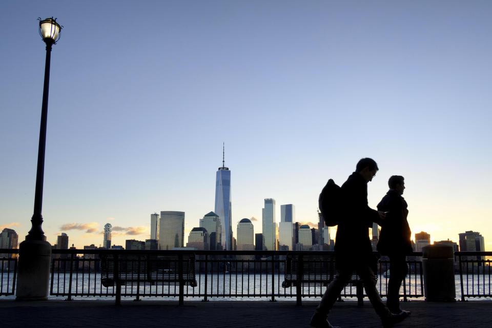Early morning commuters on the New Jersey side of the Hudson River walk to work past the New York City skyline, Tuesday, Dec. 18, 2018, in Jersey City, N.J. (AP Photo/J. David Ake)