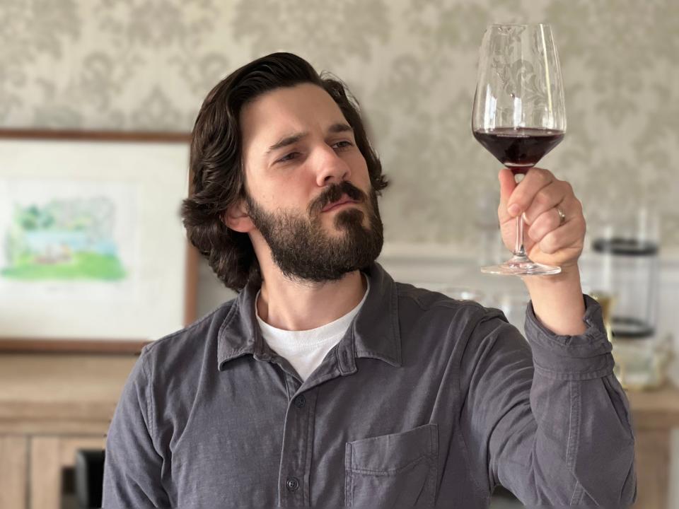 The author looks up and examines a glass of wine.