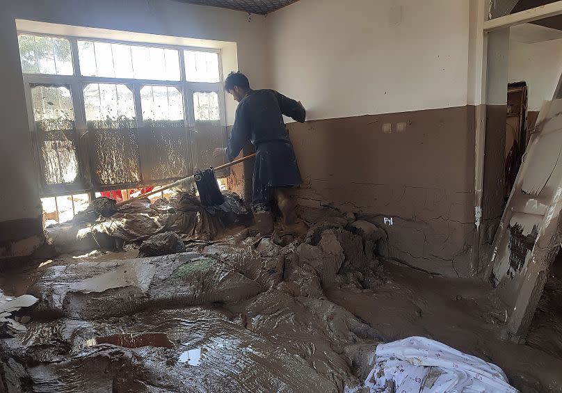 An Afghan man collects his belongings from his damaged home after heavy flooding in Baghlan province, in northern Afghanistan, Sunday, May 12, 2024.