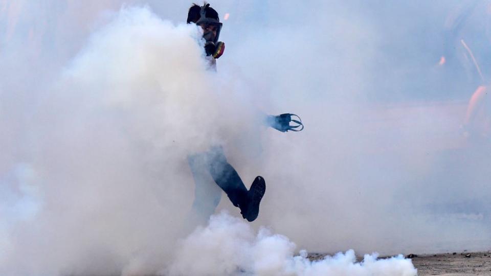 Manifestante devolviendo una bomba lacrimógena.