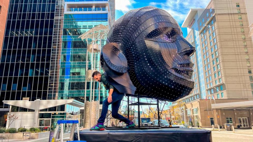 Scott Hallock helps install part of the Limelight Talking Heads installation on City Plaza in downtown Raleigh Thursday, Nov. 30, 2023. The art installation is the headliner of this year’s Illuminate Art Walk.