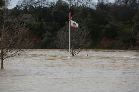 The California flag waves in flooded Riverbend Park as water is released from the Lake Oroville Dam after an evacuation was ordered for communities downstream from the dam in Oroville, California, U.S. February 13, 2017. REUTERS/Jim Urquhart
