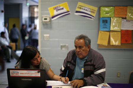 Maria Renteria (L), 30, explains health insurance options to Jesus Dominguez, 63, who is uninsured, at an enrollment event in Cudahy, California March 27, 2014. REUTERS/Lucy Nicholson